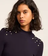 Blusa azul marino de mangas largas, confeccionada en rib con viscosa, cuello alto y perlas artificiales aplicadas en los hombros.