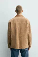 Chaqueta relaxed fit de piel con acabado serraje en color tostado, con cuello de solapa combinado a contraste, bolsillos de plastrón con solapa en la cadera y cierre frontal de botonadura.