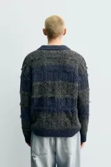 Polo de punto con textura, diseño de rayas horizontales en tonos gris y azul, cuello solapa con cierre frontal de botones y mangas largas con terminaciones en rib.