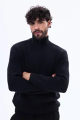 Buzo tejido de punto acanalado en color negro, con cuello alto y cierre frontal parcial. Presenta mangas largas y puños ajustados.