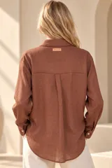 Camisa de lino color mostaza, de corte clásico con cuello camisero, manga larga y cierre frontal abotonado.