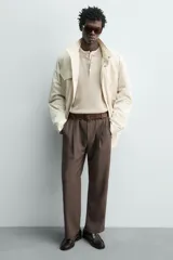 Mocasines de vestir tipo loafer para hombre, confeccionados en cuero marrón oscuro con acabado brillante. Presentan diseño clásico de antifaz en el empeine, costuras visibles en relieve y suela plana con un ligero tacón.