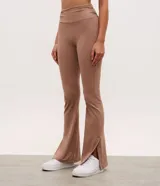 Pantalón deportivo de tiro alto con corte flare, confeccionado en microfibra elástica. Presenta un diseño ajustado en caderas y muslos con una apertura acampanada desde la rodilla y detalle de tajo lateral en el ruedo.