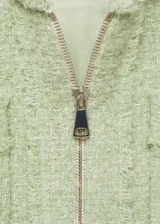Chaqueta de corte recto confeccionada en tejido tweed con mezcla de algodón y lana. Presenta cuello redondo, cierre frontal con cremallera y cuatro bolsillos de parche en la parte delantera con bordes deshilachados.