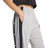Pantalón Adidas Adibreak de color gris, con cintura elástica y una banda lateral negra con botones a presión y las clásicas tres franjas blancas de la marca. Incluye el logo de Adidas Originals y etiqueta bordada en la parte inferior de la pierna.