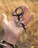 Collar tipo gargantilla con dije de flor metálica de acabado brillante, suspendido de un cordón doble de seda natural teñido a mano en color rojo.