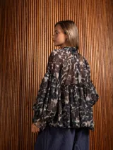 Blusa de gasa con estampado abstracto en tonos oscuros, cuello redondo con lazo ajustable, corte holgado con frunces y mangas largas abullonadas con puños elásticos.