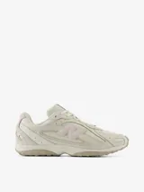 Championes New Balance modelo U204L, de color blanco con detalles en rosado pastel y suela beige. Presentan diseño inspirado en el running de los 2000 con superposiciones arqueadas y el logo 'N' en el lateral.