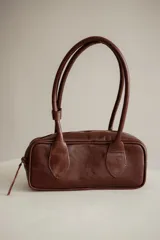 Cartera estilo baguette de cuero color marrón, con doble asa de hombro y cierre de cremallera. Hecha a mano en Uruguay.