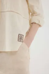 Camisa de lino blanca, de silueta oversize y calce relajado, con mangas largas y detalles de puntillas en la delantera.