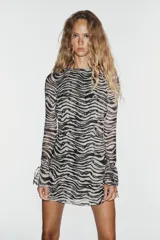 Vestido corto de tul con estampado animal print tipo cebra, escote barco y mangas largas acampanadas con lazadas ajustables. Cuenta con espalda abierta con detalle de lazada superior.