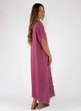 Vestido largo de lino color terracota, con escote en V y detalles de flecos en el cuello, mangas y en la parte inferior de la falda.