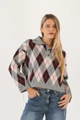 Sweater de tejido de punto con diseño de rombos en tonos gris, bordó y rosado. Presenta cuello polo con cierre frontal de dos botones y mangas largas de corte holgado.