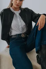 Campera bomber de cuero color marrón, con mangas abullonadas, puños elásticos y cierre frontal con botones a presión.