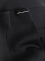 Pantalón negro de punto técnico, corte slim, pierna acampanada con aberturas traseras, talle medio, cierre de cremallera oculto y detalles de costuras verticales.