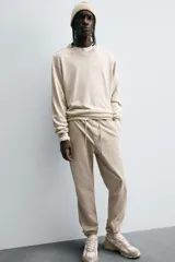 Pantalón tipo jogger de corte slim fit, confeccionado en tejido de algodón con elasticidad. Presenta cintura elástica ajustable con cordón, bolsillos frontales, bolsillos traseros de vivo y bajos con puños elásticos.