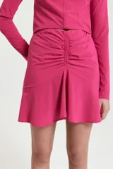 Minifalda fucsia de elastano, ajustada al cuerpo, con detalle de frunces en el frente, volado en el ruedo y cintura con elástico interno.