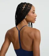 Top corto ajustado color marrón oscuro, confeccionado en microfibra, con escote halter y tirantes finos que se unen en la espalda.