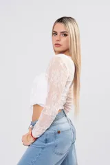 Blusa de encaje floral blanco con transparencias, mangas largas, escote cruzado y lazos frontales con volados.
