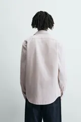 Camisa slim fit de algodón, color beige con rayas verticales blancas. Presenta cuello italiano, manga larga con puño de botón y cierre frontal de botonadura.