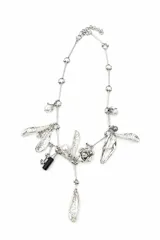 Collar plateado de diseño asimétrico con dijes colgantes en forma de pétalos texturados, perlas sintéticas, una flor esculpida y una cuenta cilíndrica negra.