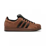 Championes Adidas modelo Superstar II, confeccionados en gamuza color marrón con las icónicas tres tiras laterales en cuero negro. Presenta la clásica puntera de goma texturizada, lengüeta negra y suela de goma al tono.