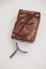 Billetera pequeña con cierre perimetral, confeccionada en material con estampado de piel de serpiente y detalle de bordado en relieve de color negro.