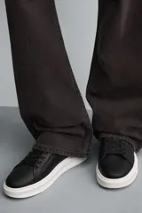 Zapatillas deportivas blancas de caña baja, con detalle de color negro en el talón y suela con volumen.