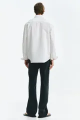 Camisa H&M de algodón Oxford blanca, con cuello americano, bolsillo superior en el pecho y mangas largas con puño abotonado.
