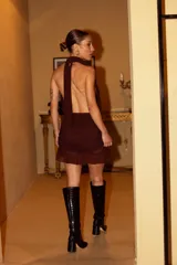 Vestido corto de microtul negro con escote profundo tipo halter, detalle de frunces en la falda y terminación con volado en el ruedo. Incluye un cinturón ancho con hebilla metálica dorada.