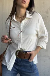 Camisa de color natural, manga larga, con detalle de bordado geométrico a lo largo de la botonadura frontal y cuello clásico.