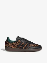 Championes Adidas Samba OG con estampado de guepardo, detalles en cuero negro, forro interior verde y suela marrón. Zapatilla de corte bajo con cordones negros y las tres tiras características de Adidas en cuero negro.