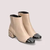 Botas cortas color beige con puntera negra charol y tacón bajo acolchado con diseño de rombos.