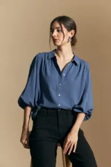 Camisa de manga larga color celeste, con cuello clásico, cierre frontal con botones y puños elastizados con volados. Presenta un diseño fluido con detalle de vainilla en la espalda.