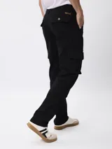 Pantalon cargo de gabardina color negro, con corte regular fit, tiro medio, cierre de boton y cremallera, y bolsillos laterales tipo cargo.