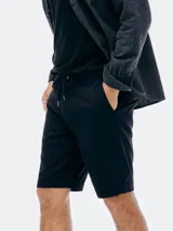 Bermuda de gabardina color beige con cintura elástica y cordón ajustable. Presenta bolsillos laterales y ruedo con dobladillo.