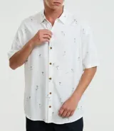 Camisa de viscosa con estampado de palmeras, corte relaxed, cuello inglés, manga corta y botones contrastantes.