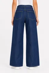 Pantalón jean de tiro alto y corte ancho, color celeste claro, con bolsillos laterales y cinto de la misma tela con hebilla metálica circular doble.