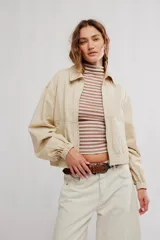 Campera bomber de sarga color beige, de calce amplio, con cuello con solapa, cierre frontal a cremallera, bolsillos al frente y puños y cintura elastizados.