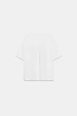 Camiseta de corte oversize confeccionada en algodón flamé, con cuello redondo y manga corta. Presenta un diseño con efecto desgastado, detalles de roturas en el tejido y estampado de texto a contraste en la parte frontal.