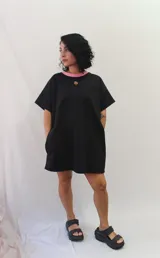 Remerón tipo vestido de corte holgado y manga corta, con cuello redondo en contraste y bolsillos laterales. Presenta un pequeño aplique decorativo en el pecho.