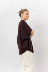 Sweater de tejido de punto color negro, con cuello semi alto y mangas cortas amplias. Presenta una silueta relajada y caída fluida.