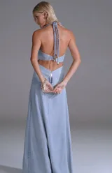 Vestido largo de denim celeste claro con escote halter, nudo central en el pecho, aberturas laterales en la cintura y tajo frontal en la falda.