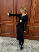 Vestido midi de color negro, confeccionado en tejido plisado con escote en V y mangas largas acampanadas.