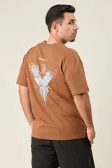 Remera marrón de corte holgado con estampado de un ave y texto en la espalda.