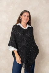 Poncho negro de tejido calado con destellos brillantes y terminación de flecos en el ruedo.