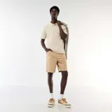 Bermuda ligera color beige, de corte clásico con bolsillos laterales y trabillas para cinturón.