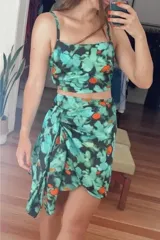 Top corto de breteles finos con escote recto, confeccionado en tela liviana con estampado abstracto en tonos verdes, negros y naranjas.