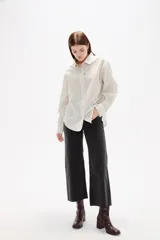 Camisa de algodón con diseño de rayas verticales finas en tonos neutros, corte holgado, cuello camisero y cierre frontal con botones.