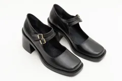 Guillerminas de cuero charol negro con punta cuadrada, taco ancho y correa sobre el empeine con doble hebilla dorada.